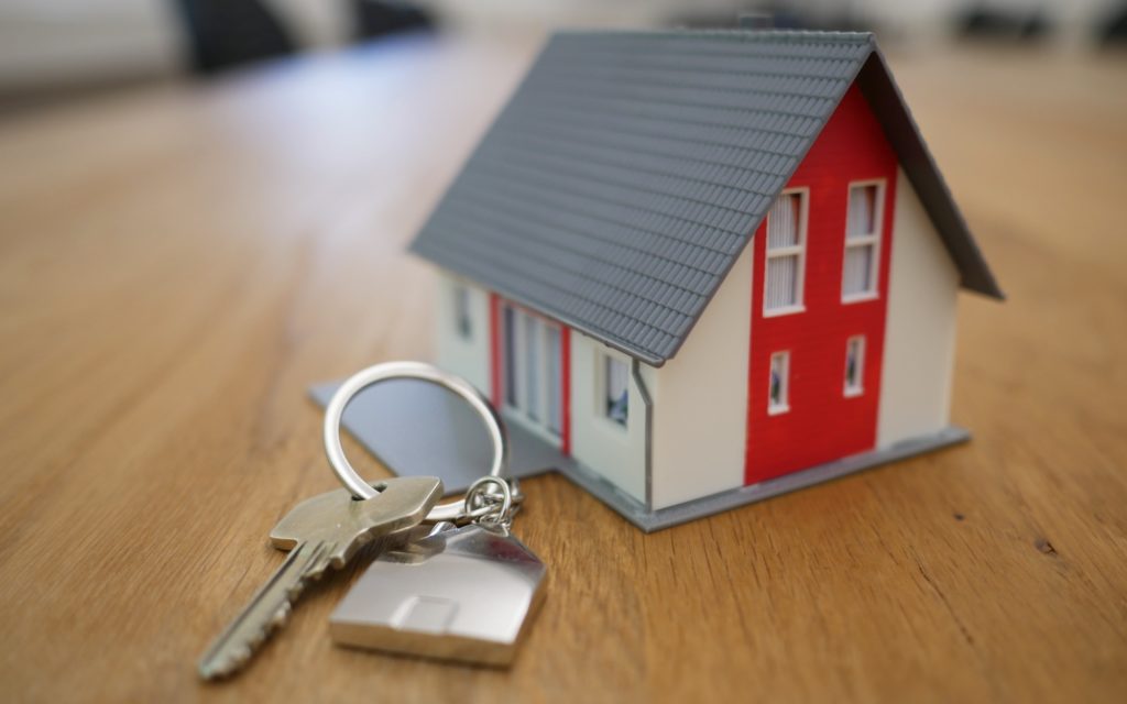 House key on a ring sitting next to a tiny model house